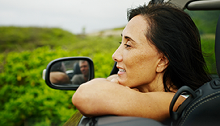A woman looking out of an open car window and smiling