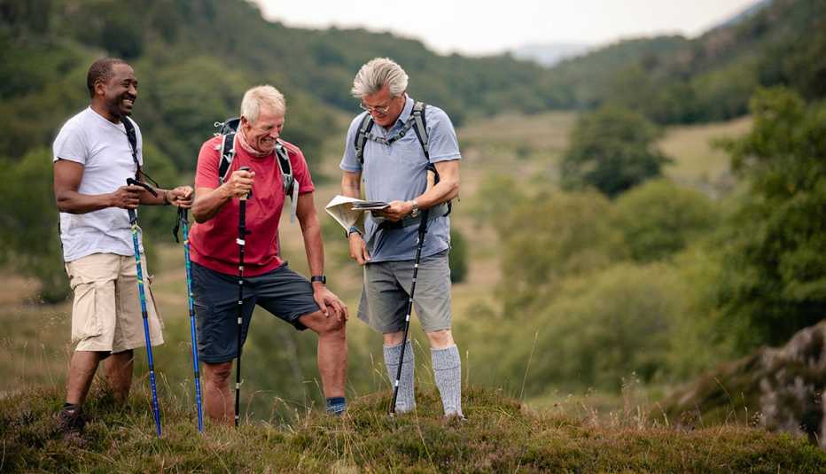 Three men hiking with hiking poles and looking at a map