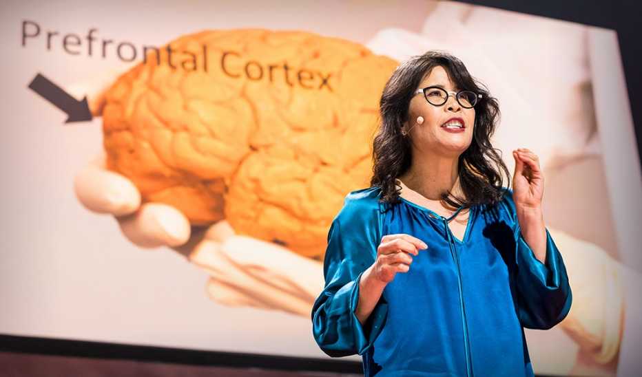 A woman, Wendy Suzuki, speaking on stage at a TED event