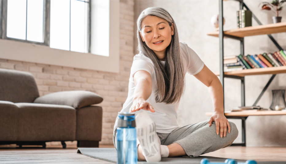 A woman sitting on the floor and doing a leg stretch