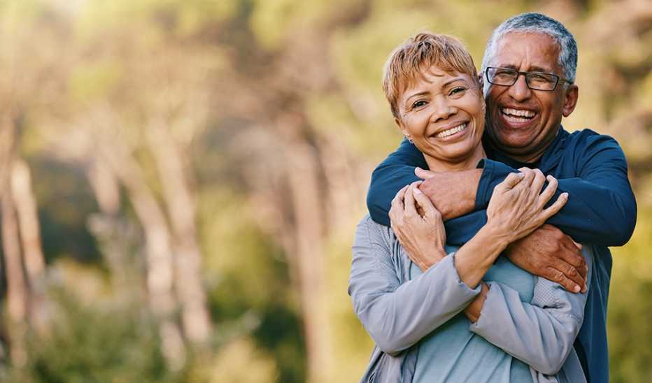 A man and woman couple smiling and hugging outside in nature