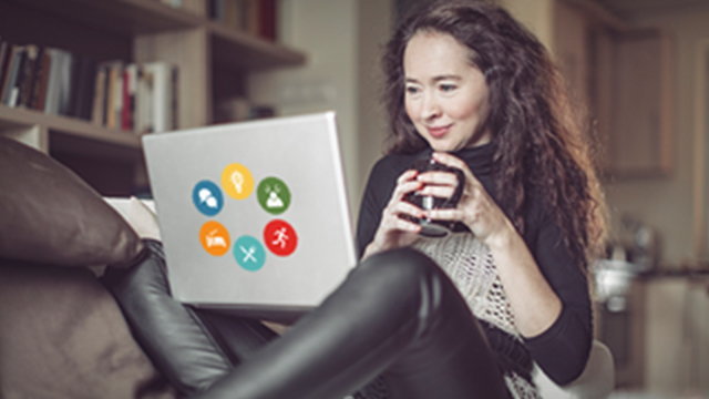 A woman drinking out of a mug with her laptop on her lap
