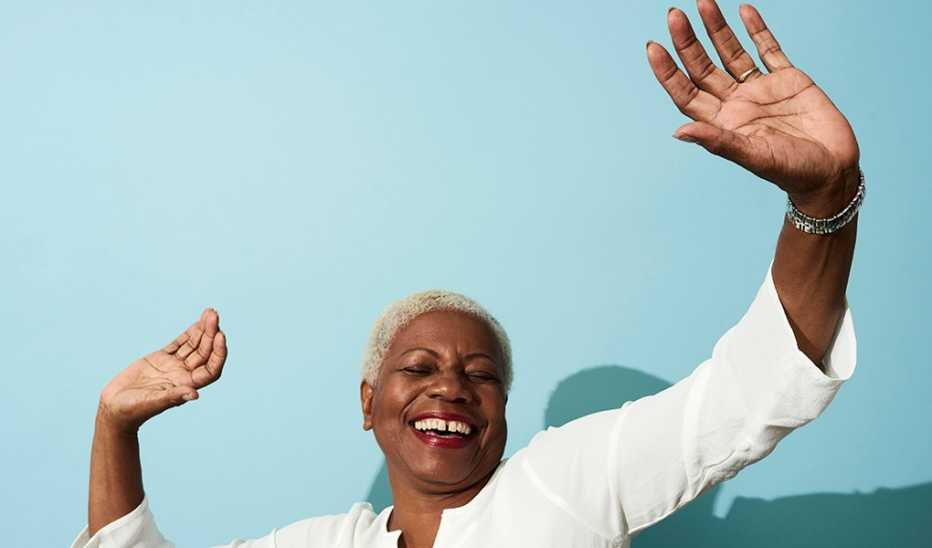 A woman smiling and dancing in front of a blank wall