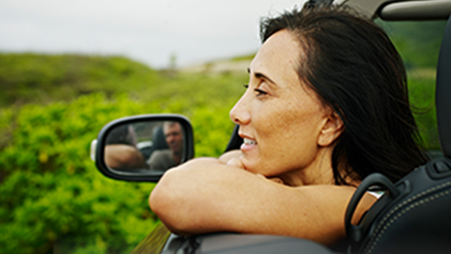 A woman looking out of an open car window and smiling