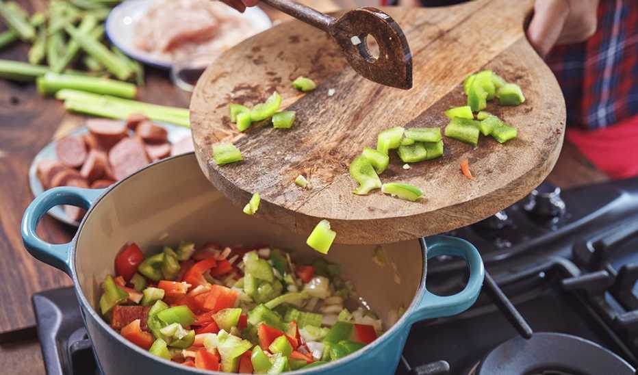 A cast iron pot of cajun-style chicken, shrimp and sausage jambalaya being prepared