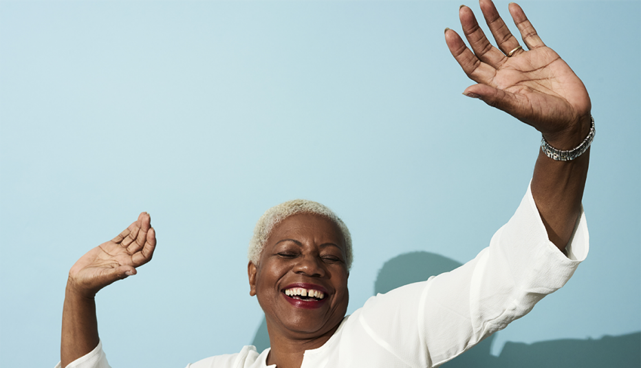 A woman smiling and dancing in front of a blank wall