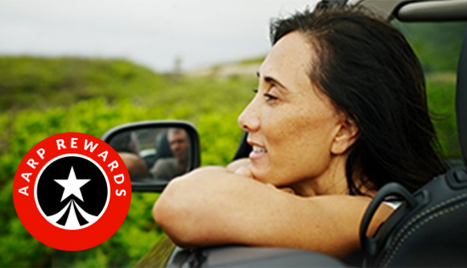 A woman looking out of an open car window and smiling