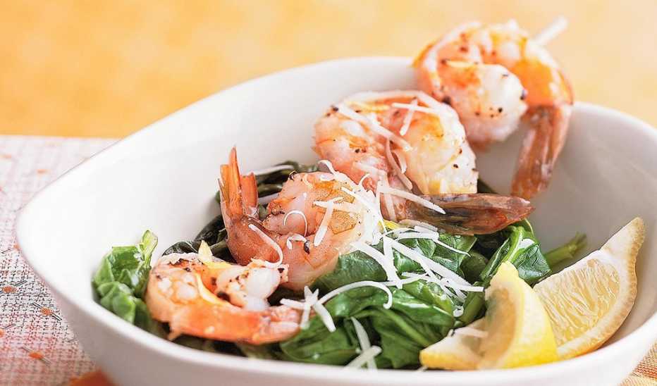 A close-up view of garlic shrimp on spinach in a bowl