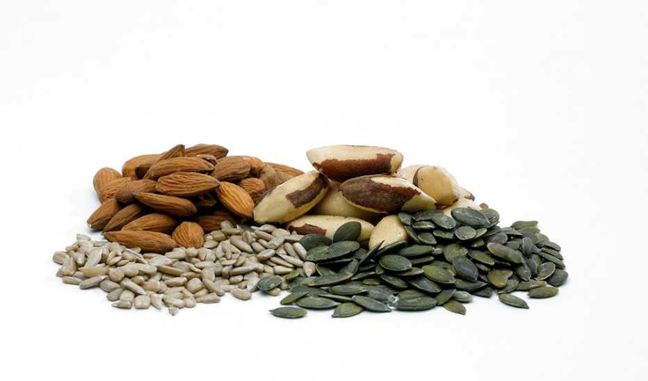 A pile of different nuts and seeds on a white background