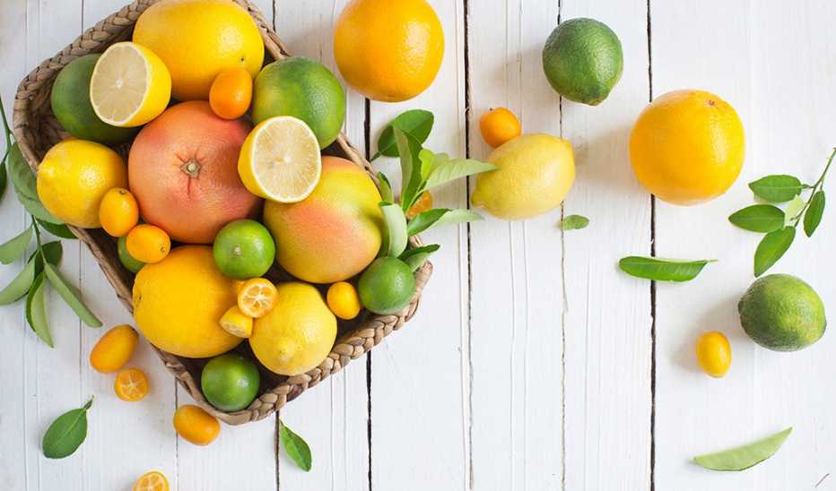 Citrus fruits in basket on rustic white wood background