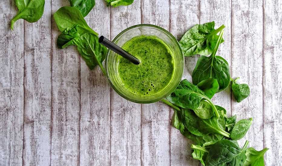 An overhead view of a green smoothie against a wooden background