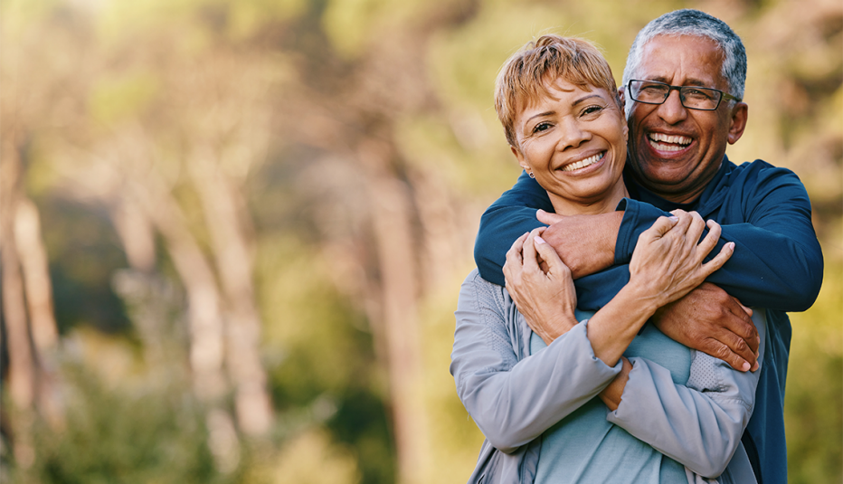 A man and woman couple smiling and hugging outside in nature
