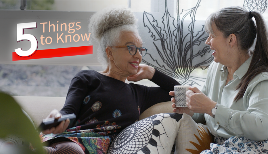 two women talk while sitting on a couch together