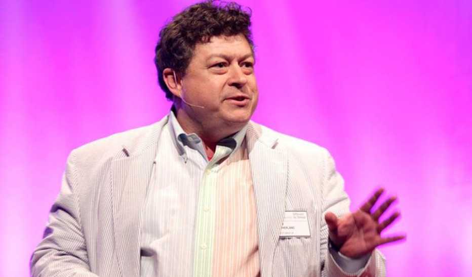 A man, Rory Sutherland, speaking on stage at a TED event