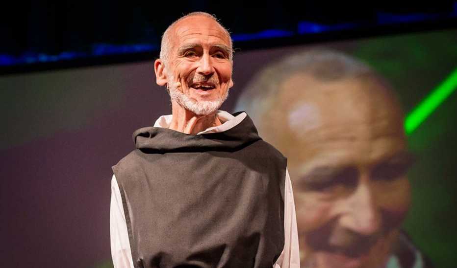 A man, David Steindl-Rast, speaking on stage at a TED event A man, David Steindl-Rast, speaking on stage at a TED event