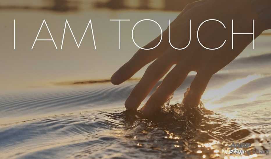 An up-close view of a hand touching water with "I Am Touch" text