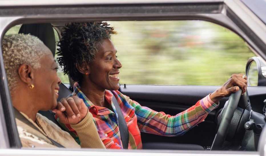 Two women smiling as one drives a car