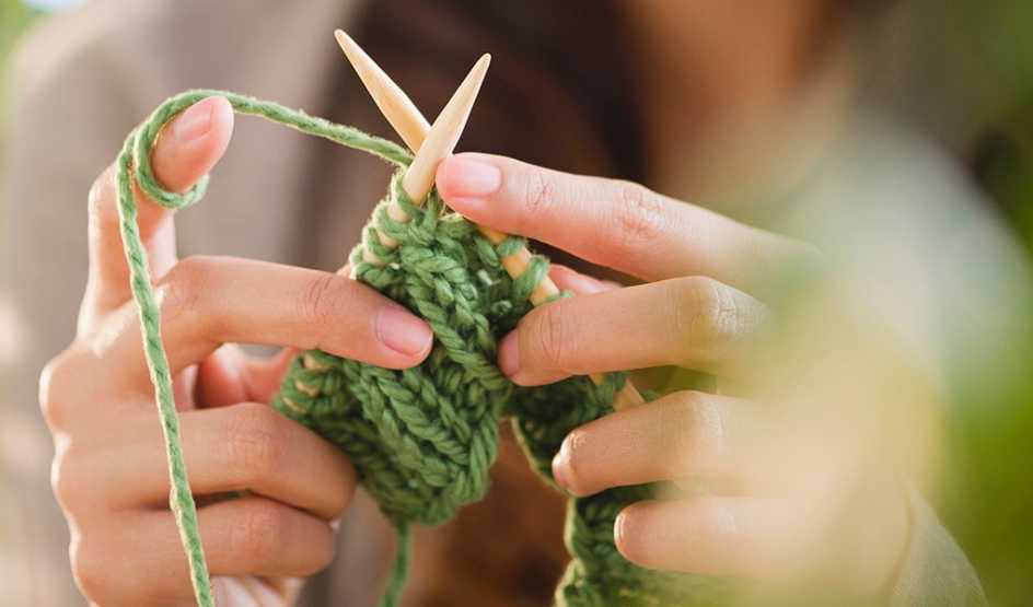 A close-up view of a person knitting with needles and yarn
