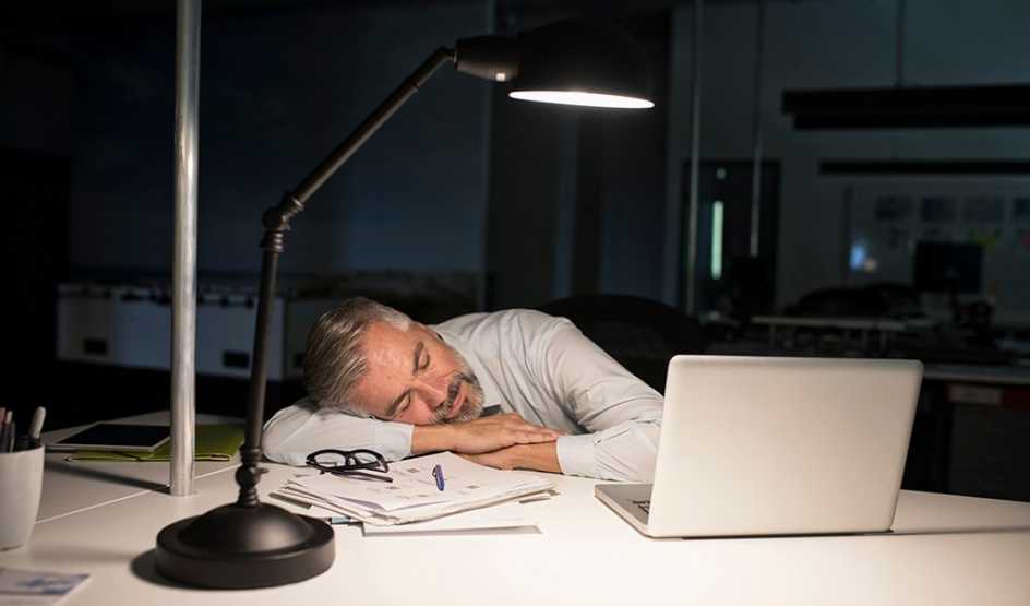 A man napping at a desk at night