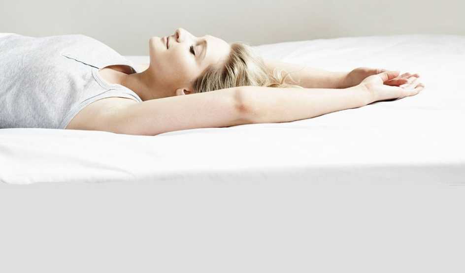 A woman lying on a bed with her eyes closed