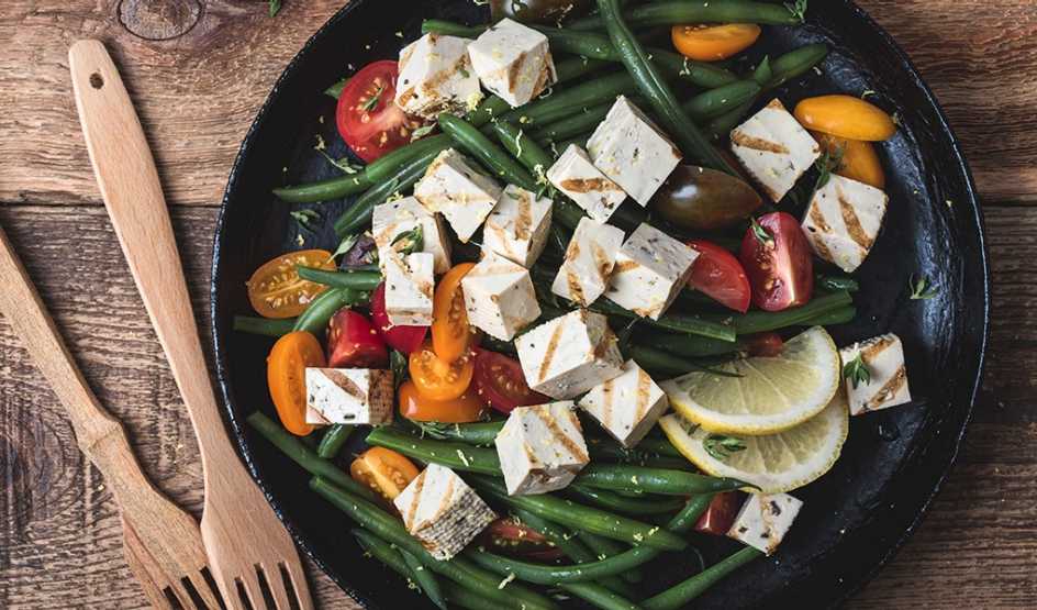 A close-up view of a green bean salad with grilled tofu in a bowl