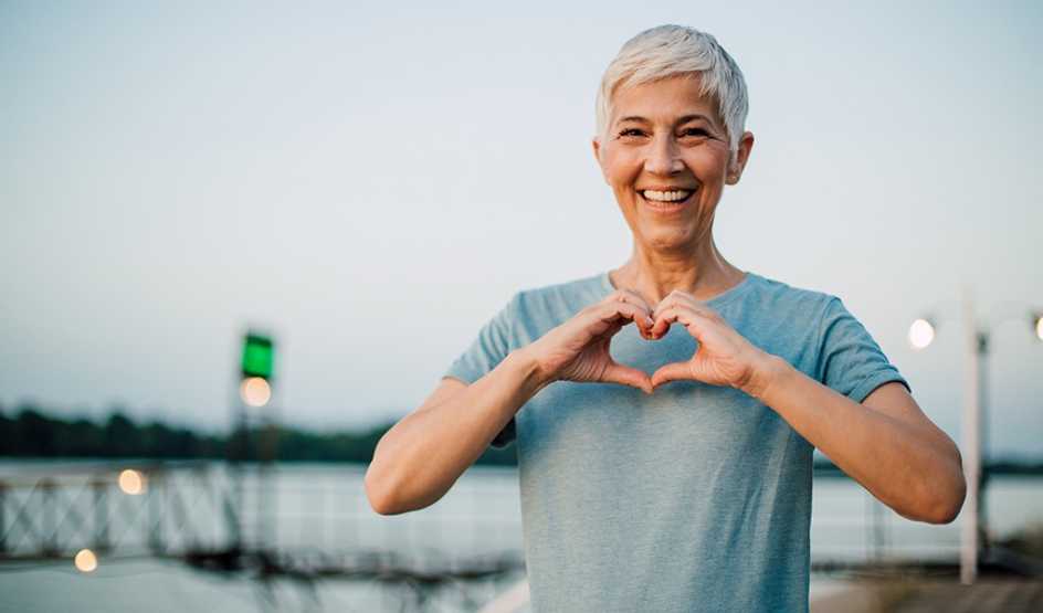 A smiling woman making a heart shape with her hands